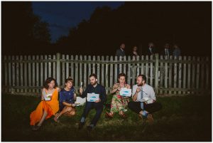 wedding guests sit on the grass eating fish and chips